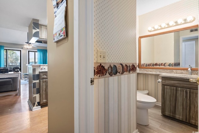 1100 Possum Trot Rd Unit C-203, North Myrtle Beach, SC 29582 - bathroom with wallpapered walls, wood finished floors, toilet, vanity, and a ceiling fan