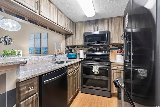 1100 Possum Trot Rd Unit C-203, North Myrtle Beach, SC 29582 - kitchen with appliances with stainless steel finishes, a sink, light stone countertops, light wood-style floors, and a textured ceiling