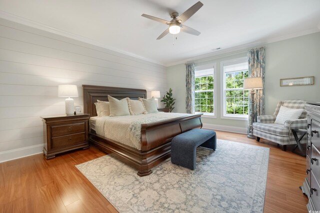 113 Trotter Trl, Georgetown, SC 29440 - bedroom featuring baseboards, crown molding, light wood-style floors, ceiling fan, and wooden walls