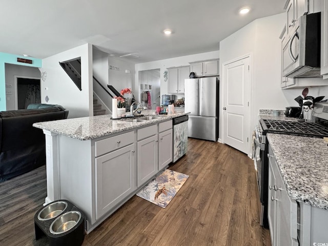 2230 Ainsley Dr, Little River, SC 29566 - kitchen with appliances with stainless steel finishes, open floor plan, dark wood-type flooring, an island with sink, and light stone counters