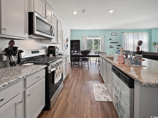 2230 Ainsley Dr, Little River, SC 29566 - kitchen featuring appliances with stainless steel finishes, wood finished floors, light stone counters, a kitchen island, and recessed lighting