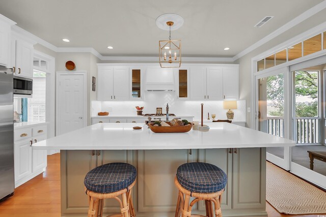 92 High Hammock Way, Pawleys Island, SC 29585 - kitchen featuring ornamental molding, light countertops, a kitchen bar, appliances with stainless steel finishes, and white cabinets