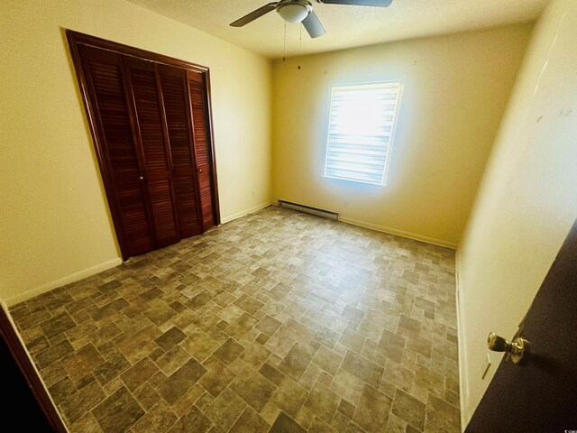 704 W Alder St, Andrews, SC 29510 - unfurnished bedroom with baseboard heating, stone finish flooring, a closet, a ceiling fan, and baseboards