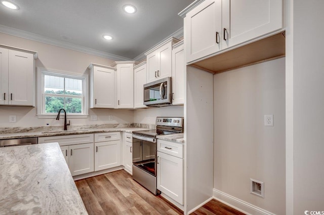 142 Temple Dr, Aynor, SC 29511 - kitchen featuring stainless steel appliances, a sink, ornamental molding, white cabinets, and light wood finished floors