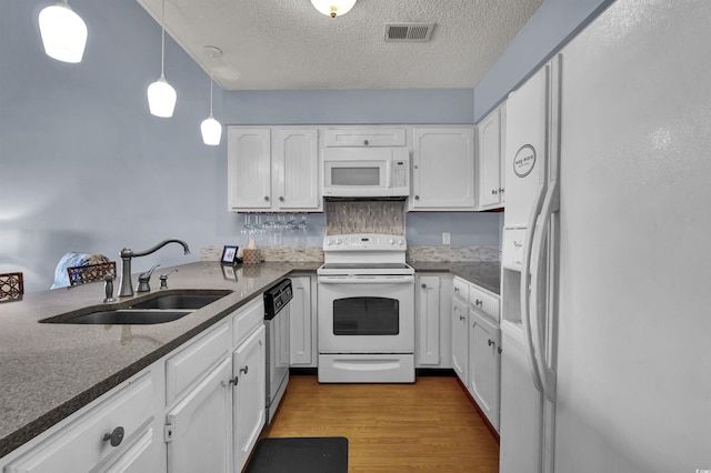 1912 Goose Creek Rd SW Unit 4302, Ocean Isle Beach, NC 28469 - kitchen with white appliances, a sink, white cabinets, a textured ceiling, and wood finished floors