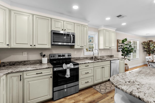1616 S Ocean Blvd, North Myrtle Beach, SC 29582 - kitchen with appliances with stainless steel finishes, a sink, light wood finished floors, ornamental molding, and light stone counters