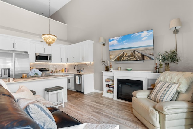 210 Double Eagle Dr Unit B-2, Surfside Beach, SC 29575 - living room with a chandelier, light wood finished floors, a towering ceiling, and a glass covered fireplace