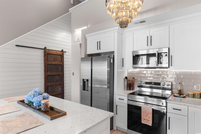 210 Double Eagle Dr Unit B-2, Surfside Beach, SC 29575 - kitchen with appliances with stainless steel finishes, a barn door, decorative backsplash, a chandelier, and white cabinetry