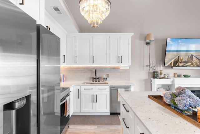210 Double Eagle Dr Unit B-2, Surfside Beach, SC 29575 - kitchen with stainless steel appliances, a sink, white cabinetry, light stone counters, and decorative backsplash