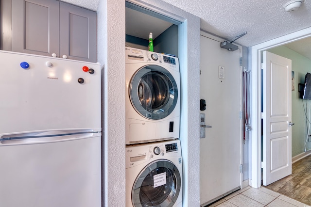 2801 S Ocean Blvd Unit 538, North Myrtle Beach, SC 29582 - washroom featuring estacked washer and dryer, a textured ceiling, and light tile patterned floors