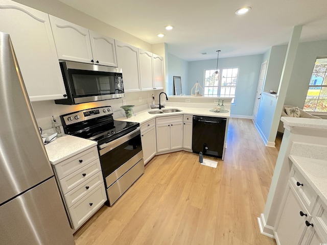 107 Pawleys Place Dr Unit 107, Pawleys Island, SC 29585 - kitchen with stainless steel appliances, a sink, light wood-style floors, white cabinets, and recessed lighting