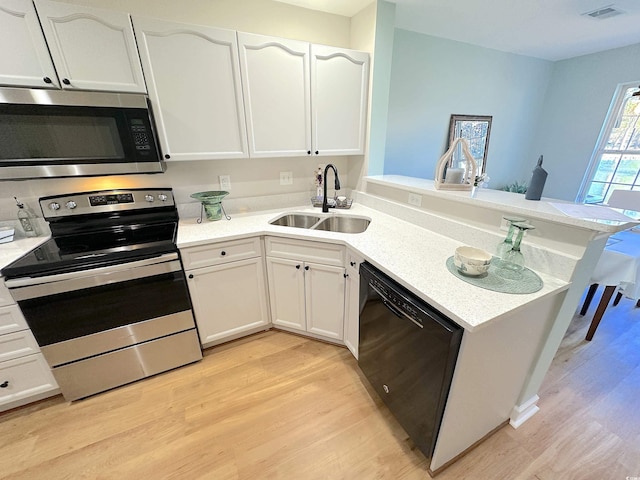 107 Pawleys Place Dr Unit 107, Pawleys Island, SC 29585 - kitchen with appliances with stainless steel finishes, a sink, a peninsula, and light wood-type flooring