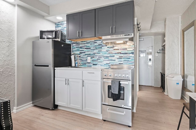 1207 S Ocean Blvd Unit 20109, Myrtle Beach, SC 29577 - kitchen featuring appliances with stainless steel finishes, under cabinet range hood, backsplash, light wood-style flooring, and a textured wall