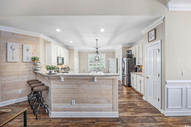 7005 Wellesley Ct, Murrells Inlet, SC 29576 - kitchen featuring appliances with stainless steel finishes, a kitchen breakfast bar, ornamental molding, a peninsula, and dark wood-type flooring