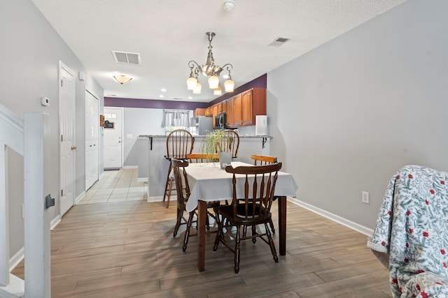 1102 Stanton Pl Unit 1102, Myrtle Beach, SC 29579 - dining space with a chandelier, light wood-type flooring, baseboards, and a textured ceiling