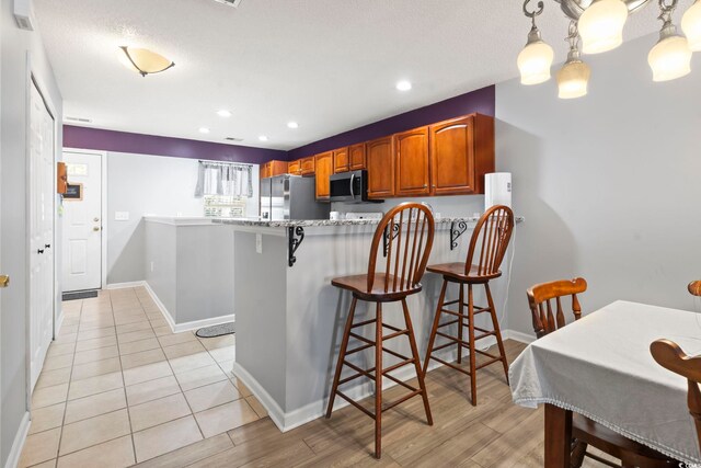 1102 Stanton Pl Unit 1102, Myrtle Beach, SC 29579 - kitchen featuring appliances with stainless steel finishes, brown cabinets, a kitchen breakfast bar, a peninsula, and baseboards