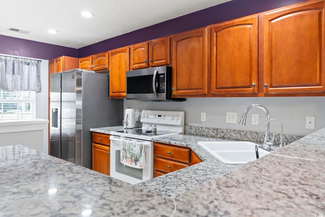 1102 Stanton Pl Unit 1102, Myrtle Beach, SC 29579 - kitchen featuring appliances with stainless steel finishes, a sink, brown cabinetry, recessed lighting, and light stone counters