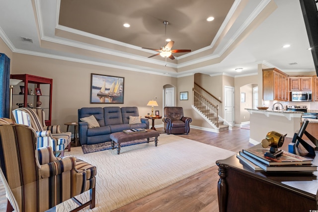 1025 Limpkin Dr, Conway, SC 29526 - living area featuring arched walkways, a tray ceiling, light wood-style floors, and crown molding