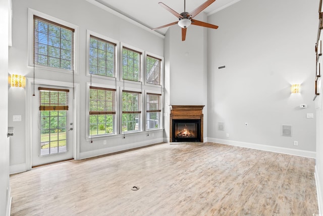 528 Chamberlin Rd, Myrtle Beach, SC 29588 - unfurnished living room with a towering ceiling, a ceiling fan, baseboards, a glass covered fireplace, and wood finished floors