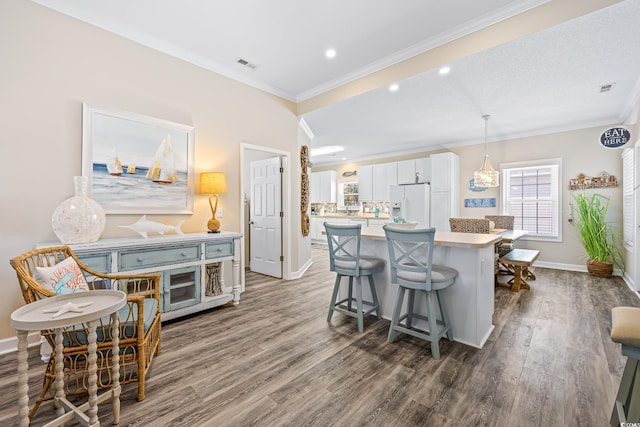 2405 Duffy St, North Myrtle Beach, SC 29582 - kitchen featuring white fridge with ice dispenser, a kitchen breakfast bar, dark wood-style floors, white cabinetry, and a center island