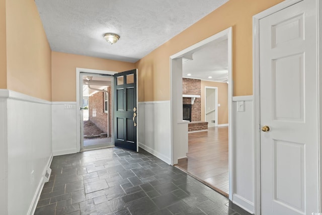 1043 S Main St, Aynor, SC 29511 - foyer with a wainscoted wall, a textured ceiling, stone tile floors, a brick fireplace, and baseboards