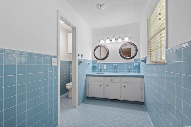 1043 S Main St, Aynor, SC 29511 - bathroom with tile walls, toilet, double vanity, a wainscoted wall, and tile patterned floors