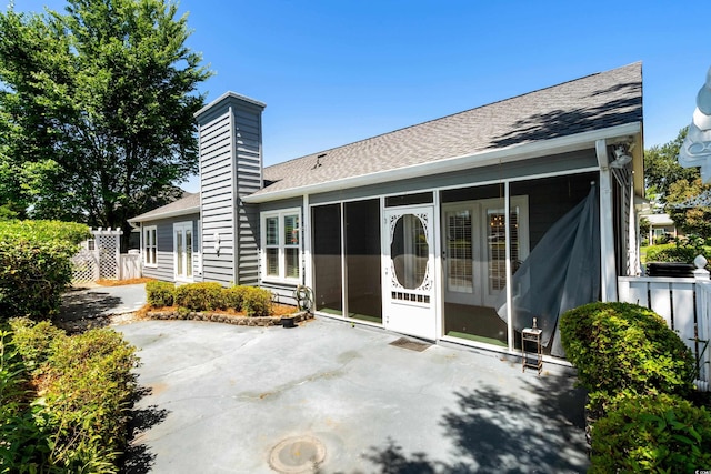 578 Circle Dr, Myrtle Beach, SC 29575 - rear view of property featuring a sunroom, roof with shingles, a patio, and a chimney