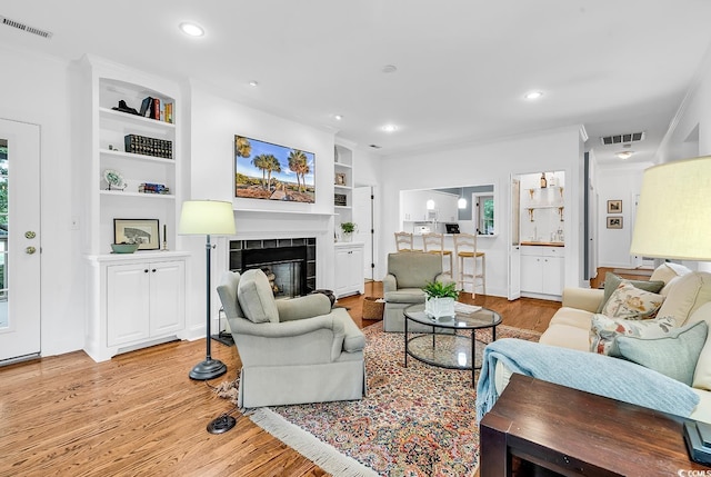 179 Golden Bear Dr Unit C4, Pawleys Island, SC 29585 - living room featuring light wood finished floors, built in shelves, a tiled fireplace, and recessed lighting