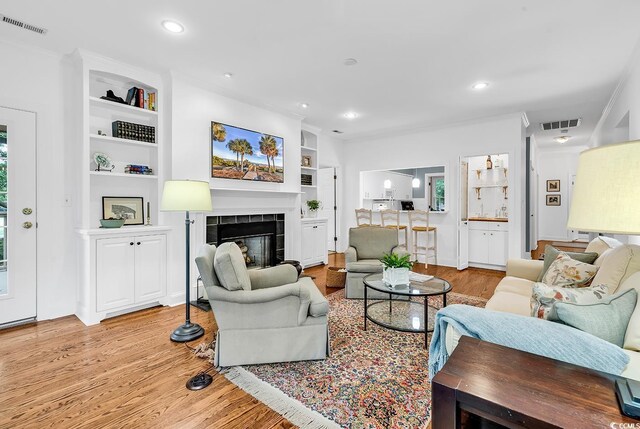 179 Golden Bear Dr Unit C4, Pawleys Island, SC 29585 - living area featuring light wood-style flooring, built in shelves, a tile fireplace, recessed lighting, and ornamental molding