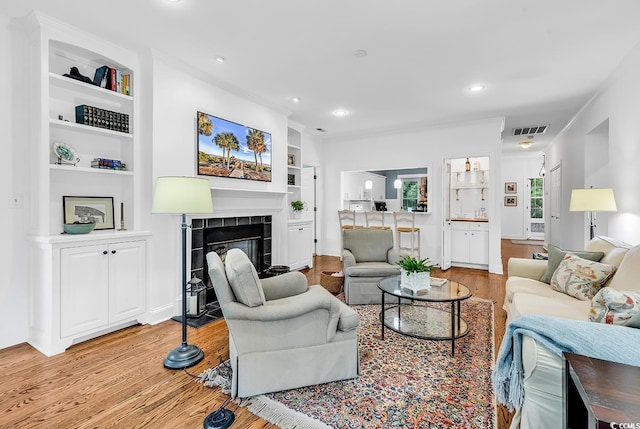 179 Golden Bear Dr Unit C4, Pawleys Island, SC 29585 - living area featuring light wood finished floors, built in shelves, a tiled fireplace, recessed lighting, and ornamental molding
