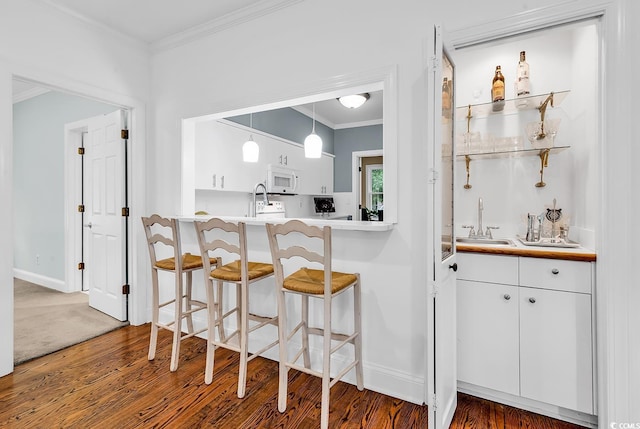 179 Golden Bear Dr Unit C4, Pawleys Island, SC 29585 - indoor wet bar featuring white microwave, crown molding, hanging light fixtures, wood finished floors, and baseboards