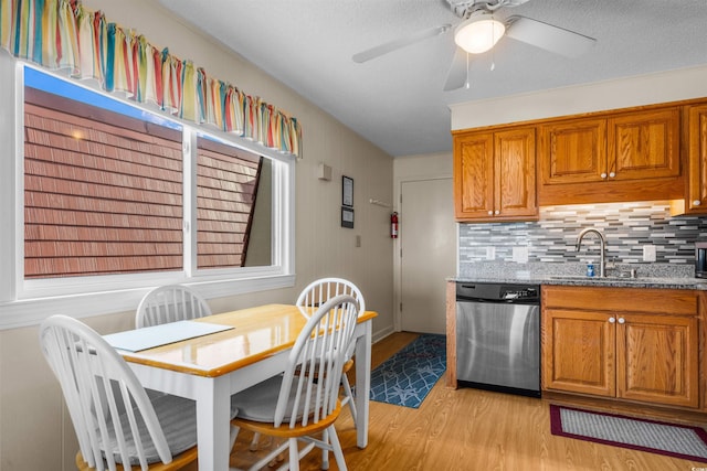6309 N Ocean Blvd Unit 14E, North Myrtle Beach, SC 29582 - kitchen featuring dishwasher, a sink, light wood-style floors, brown cabinets, and stone counters