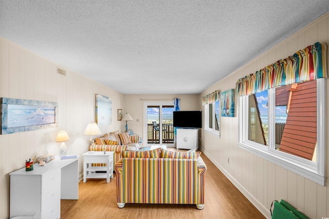 6309 N Ocean Blvd Unit 14E, North Myrtle Beach, SC 29582 - living area featuring a textured ceiling, light wood-style flooring, and wooden walls