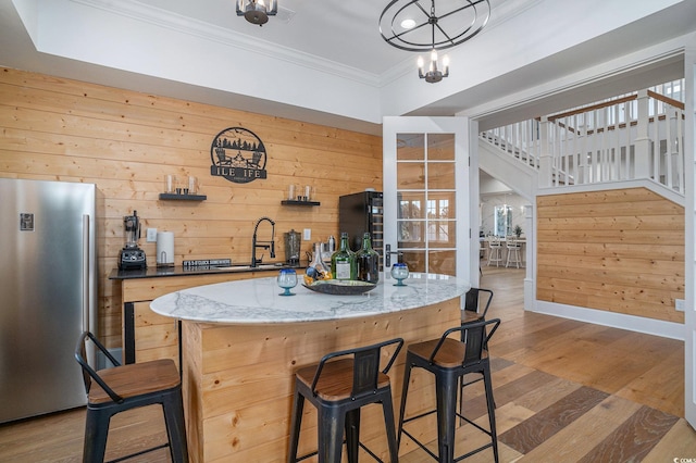 139 Pioneer Loop, Georgetown, SC 29440 - kitchen featuring freestanding refrigerator, crown molding, wooden walls, wood finished floors, and a kitchen bar