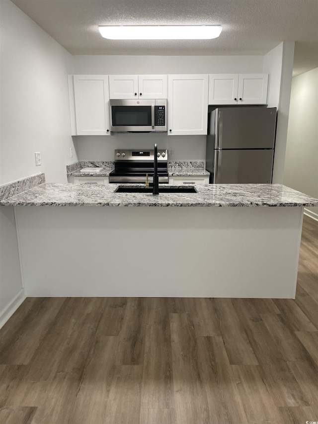 1509 N Waccamaw Dr Unit 112, Murrells Inlet, SC 29576 - kitchen with stainless steel appliances, a sink, light stone counters, and white cabinetry
