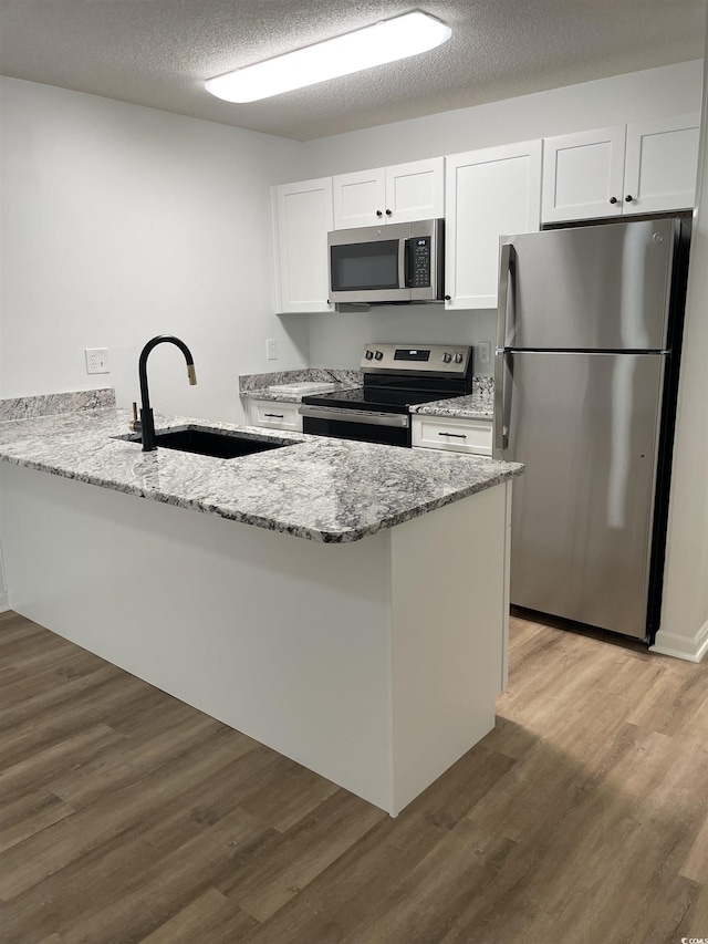 1509 N Waccamaw Dr Unit 112, Murrells Inlet, SC 29576 - kitchen featuring appliances with stainless steel finishes, a sink, white cabinetry, a peninsula, and light wood finished floors