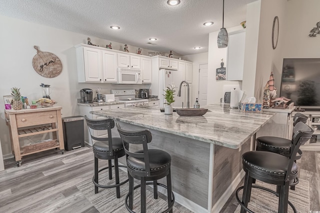 359 Harbour Reef Dr, Myrtle Beach, SC 29588 - kitchen with white appliances, a peninsula, a breakfast bar area, light wood-style flooring, and light stone countertops