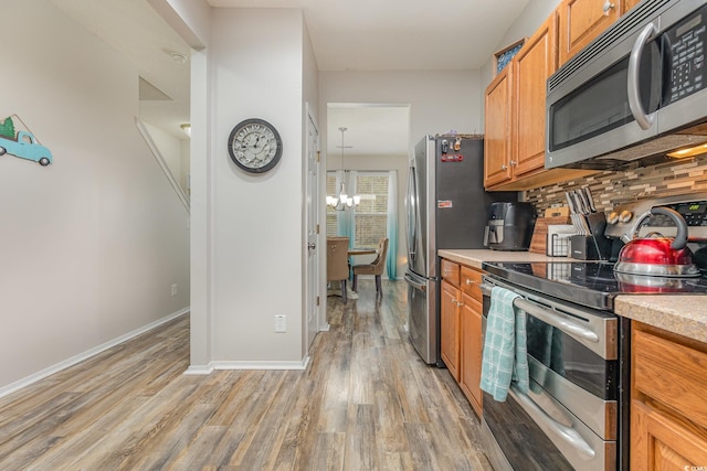 310 Kiskadee Loop Unit D, Conway, SC 29526 - kitchen with appliances with stainless steel finishes, backsplash, light countertops, a chandelier, and light wood-type flooring