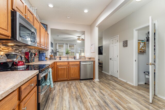 310 Kiskadee Loop Unit D, Conway, SC 29526 - kitchen with stainless steel appliances, light wood-style flooring, light countertops, brown cabinetry, and decorative backsplash