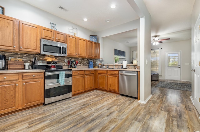 310 Kiskadee Loop Unit D, Conway, SC 29526 - kitchen featuring stainless steel appliances, backsplash, light countertops, light wood-style flooring, and brown cabinets