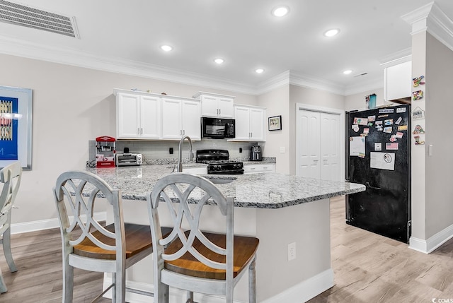 232 Je Edward Dr Unit 19, Myrtle Beach, SC 29588 - kitchen featuring black appliances, baseboards, white cabinetry, a breakfast bar area, and light stone counters