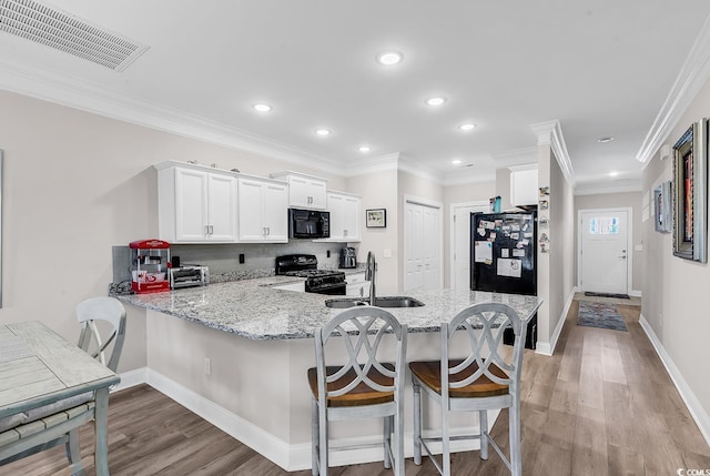 232 Je Edward Dr Unit 19, Myrtle Beach, SC 29588 - kitchen featuring black appliances, a peninsula, a sink, light wood finished floors, and recessed lighting