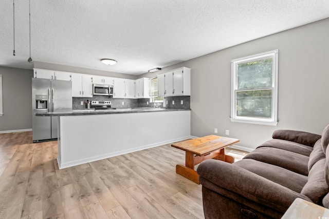 204 Elm St, Johnsonville, SC 29555 - kitchen with appliances with stainless steel finishes, open floor plan, a textured ceiling, white cabinetry, and backsplash