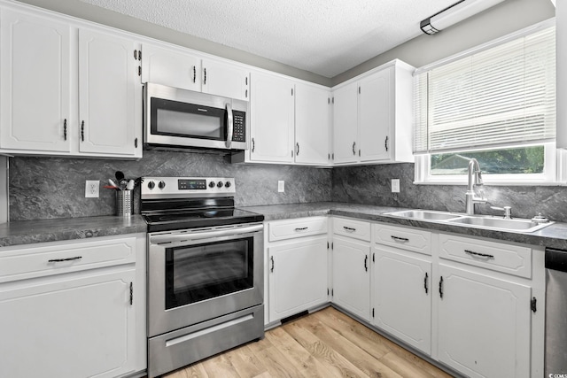 204 Elm St, Johnsonville, SC 29555 - kitchen with stainless steel appliances, a sink, white cabinetry, light wood finished floors, and a textured ceiling