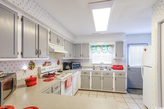 1437 Baldwin Ct Unit 1437, Little River, SC 29566 - kitchen featuring white appliances, under cabinet range hood, wallpapered walls, light countertops, and light tile patterned floors