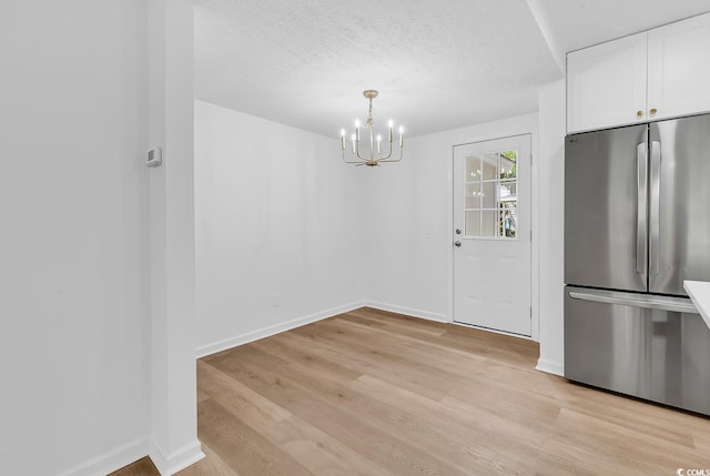 514 6th Ave S, Surfside Beach, SC 29575 - unfurnished dining area with a chandelier, light wood-style flooring, and a textured ceiling