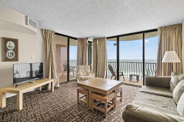 2500 N Ocean Blvd Unit 601, Myrtle Beach, SC 29577 - living area with expansive windows, a water view, a textured ceiling, healthy amount of natural light, and dark colored carpet