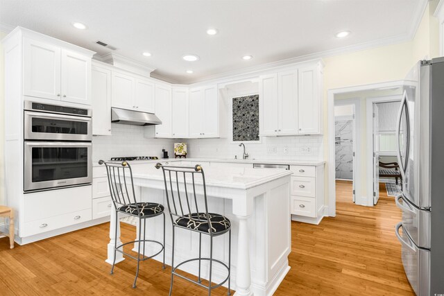 1325 Clipper Dr, North Myrtle Beach, SC 29582 - kitchen with appliances with stainless steel finishes, under cabinet range hood, white cabinets, ornamental molding, and recessed lighting