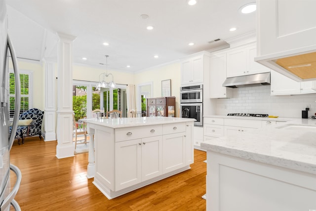 1325 Clipper Dr, North Myrtle Beach, SC 29582 - kitchen featuring under cabinet range hood, decorative columns, a center island, tasteful backsplash, and stainless steel appliances