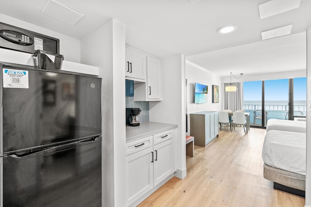7100 N Ocean Blvd N Unit 601, Myrtle Beach, SC 29572 - kitchen featuring freestanding refrigerator, white cabinets, light wood-style floors, light countertops, and pendant lighting